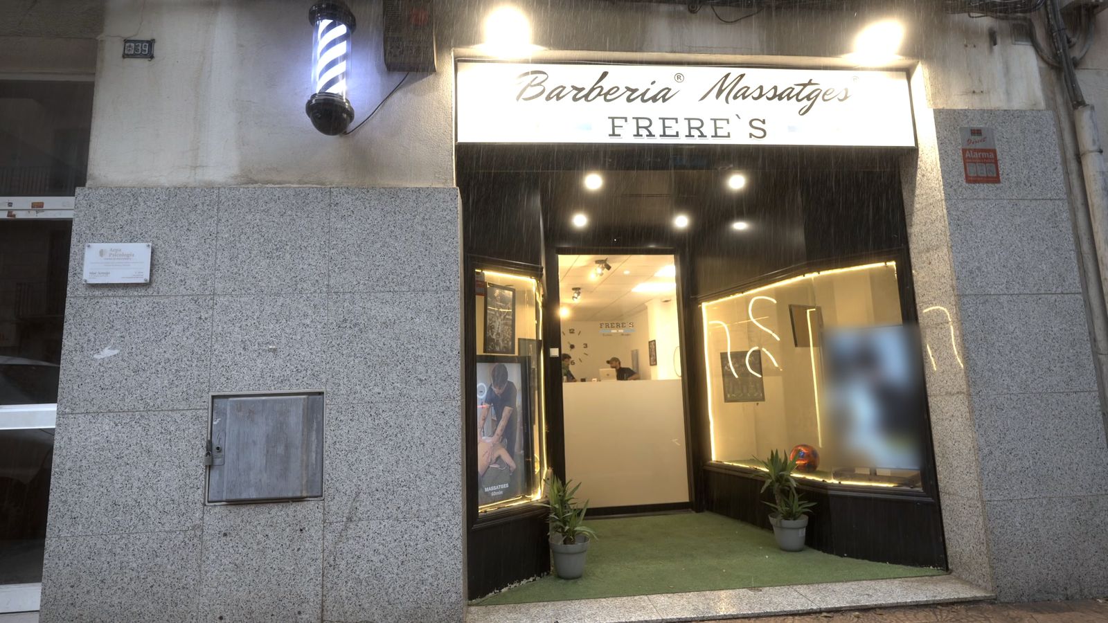 Fachada de Frere's en el Raval de Robuster, 39 de Reus, con el poste de barbero y el rótulo iluminado