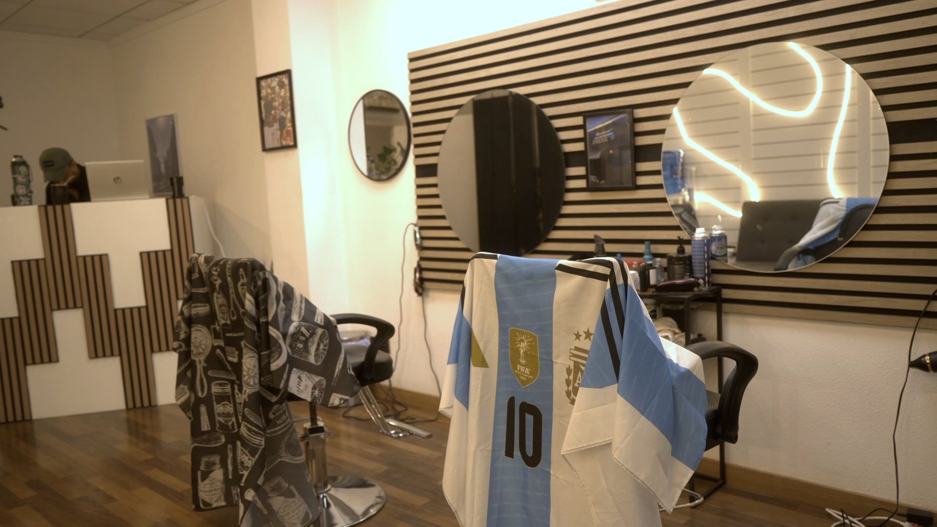 Sillón de Frere's con la capa de Argentina, delante de la pared de listones de madera y los espejos redondos